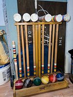 Full view of croquet set on stand showing mallets and balls