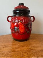 Front view of red and brown ceramic cookie jar with lid and fruit motif