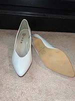 Both shoes top view showing pointed toes and white leather uppers