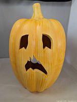 Front view of ceramic yellow jack-o'-lantern pumpkin showing carved facial openings