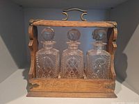 front view of wooden tantalus holding three crystal decanters
