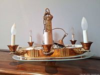 Side view showing full circular brass frame, five candle sockets and bulbs, central column and chain