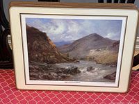 Large placemat showing river valley artwork, cream border, cork backing visible on stack edge
