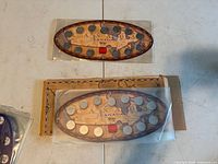 Front view of two oval 1999 Millennium coin sets in sleeves on table