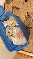 Overview of blue tote containing multiple ceramic Christmas village buildings and cords
