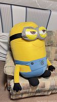 Front view of large Minion plush seated on chair