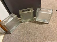 Three square glass blocks standing upright showing ribbed faces