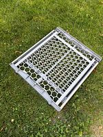 Gate folded flat on grass showing hexagonal mesh panel and overall size