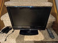 Front view of Hisense 19-inch TV on stand with remote and power adapter