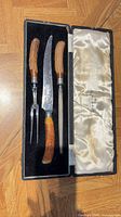 Knife, fork, and steel in open fitted case showing antler handles and satin lining