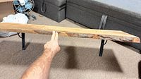 Front view of live edge shelf mounted on two black brackets