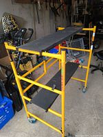 Side view showing yellow frame, two black platforms, casters