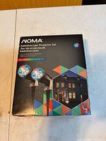 Front of retail box showing two projectors casting multicolor patterns on house