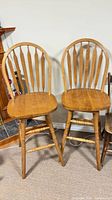 Two oak swivel Windsor spindle-back bar stools with turned legs and stretcher bars