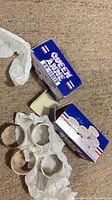Four silver-plated napkin rings with original Queen Anne boxes and tissue shown on carpet