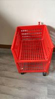 Full view of red two-tier plastic cart on casters