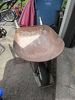 Full front view showing rusted metal tub, wood handles, single wheel