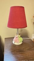 Full view of lamp with red shade on wooden surface