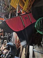 Full view of red and black dog life jacket hanging in storage