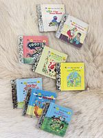 All eight miniature board books arranged on rug, covers visible
