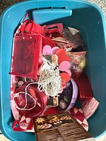 Teal tote showing assorted red/pink gift bags, heart cut-outs, string lights, ribbons, plastic eggs