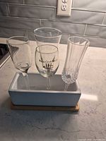 Three stemmed glasses placed in ceramic planter on bamboo tray