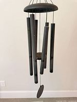 Full view of black metal wind chime showing six tubes and windcatcher