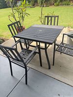 Square black aluminum patio table with four matching chairs shown on patio