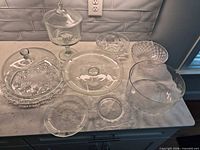 All eight clear glass serveware pieces grouped on countertop