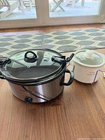 Large stainless and small white slow cookers side by side