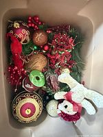 Box with large red and gold ball ornaments, coconut-look ornament, Offray ribbon spool, artificial greenery with red berries, plush teddy bear, red cardinal ornament, glitter gold ball