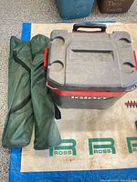 Cooler closed with green chair bag beside