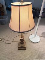 Brass/bronze table lamp with fabric shade beside white floor lamp pole