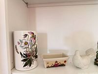 Left side close-up of cylindrical vase, rectangular dish and dove figurine