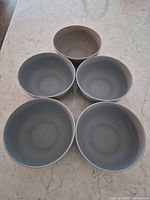 Five gray bowls arranged on countertop