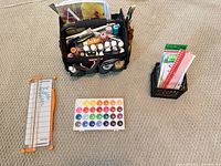 Overall lot showing tool caddy, watercolor palette, paper trimmer and crate with papers