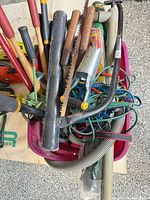 Tub filled with assorted hand tools, bungee cords, hoses