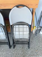 Two folded metal-frame chairs leaning against workbench