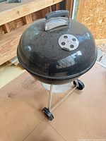 Front angle view of Weber black kettle grill with lid and ash catcher