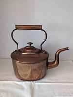 Side view of copper brass Burt Brothers dovetail kettle showing gooseneck spout, lid, and hollow handle