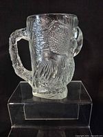 Front view of clear pressed glass stein showing bird figure and handle detail