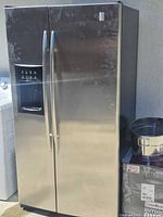 Full view of stainless steel GE side-by-side refrigerator/freezer showing dual doors and dispenser
