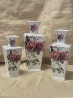 Front view of all three porcelain vases showing rose decals and relative sizes