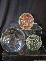 Front view of all three glass sphere paperweights on acrylic risers