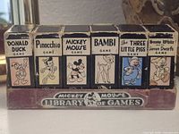 Front view of all six boxed games in display stand