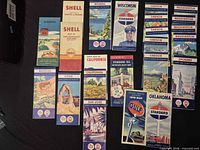Group of vintage folding road maps from Shell, Standard, Gulf etc. spread on table
