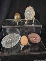 Group of eggs on stands and clear glass egg