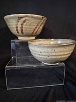 Two bowls on risers showing exterior glaze and decoration