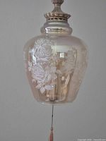 Close-up of etched rose pattern on iridescent amber glass shade