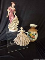 Group shot of pink dress figurine, lace half-doll, and floral vase